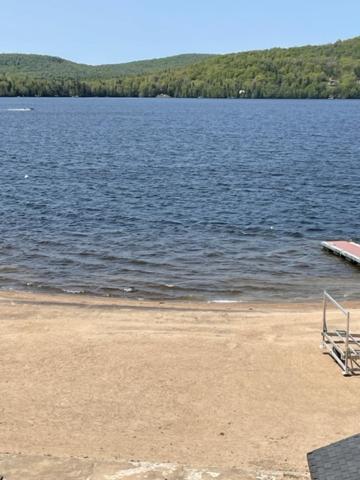 圣多纳特蒙卡尔姆Condo Lac Archambault 298的坐在湖畔沙滩上的椅子