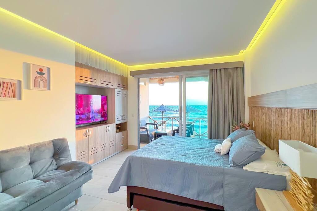 San SilvestreSuite privada frente al mar.的一间卧室配有一张床、一张沙发和一台电视