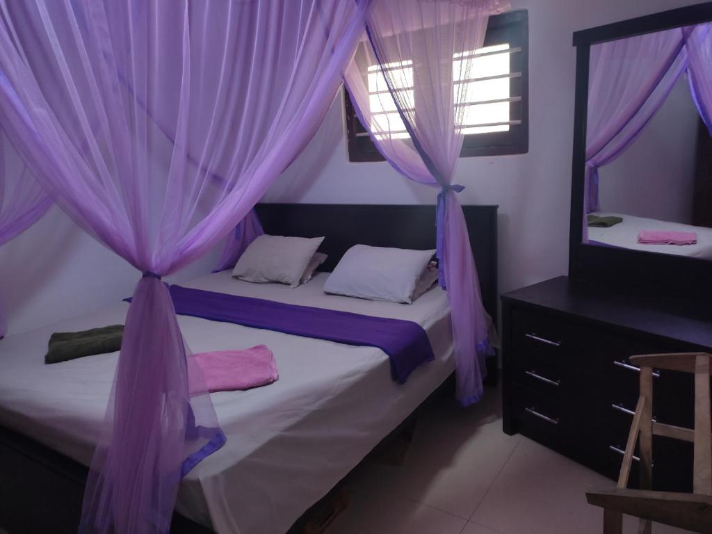 KamburugamuwaRed Rose Villa Mirissa的一间卧室配有紫色窗帘和一张带镜子的床