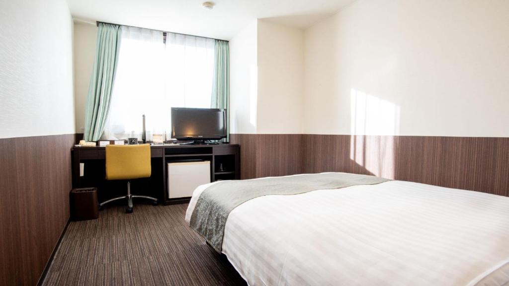 大津le Lac HOTEL Otsu Ishiyama的一间卧室配有一张床和一张书桌及电视