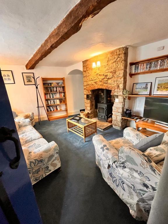 汤顿The Snuggery Cottage的客厅设有两张沙发和一个石头壁炉