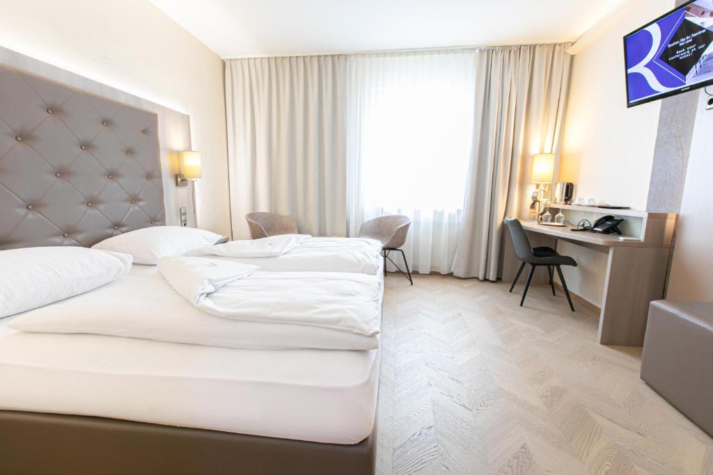 施韦夏特Das Reinisch Hotel & Restaurant的酒店客房配有两张床和一张书桌