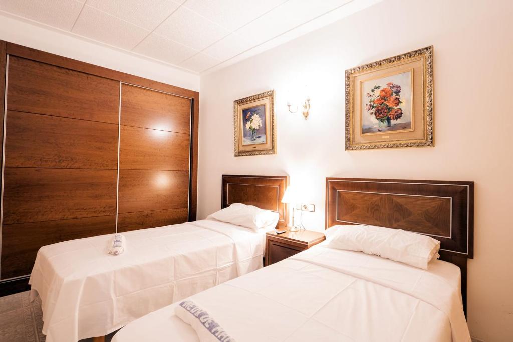 皮内达德马尔L'Hostalet GuestHouse的配有白色床单的酒店客房内的两张床