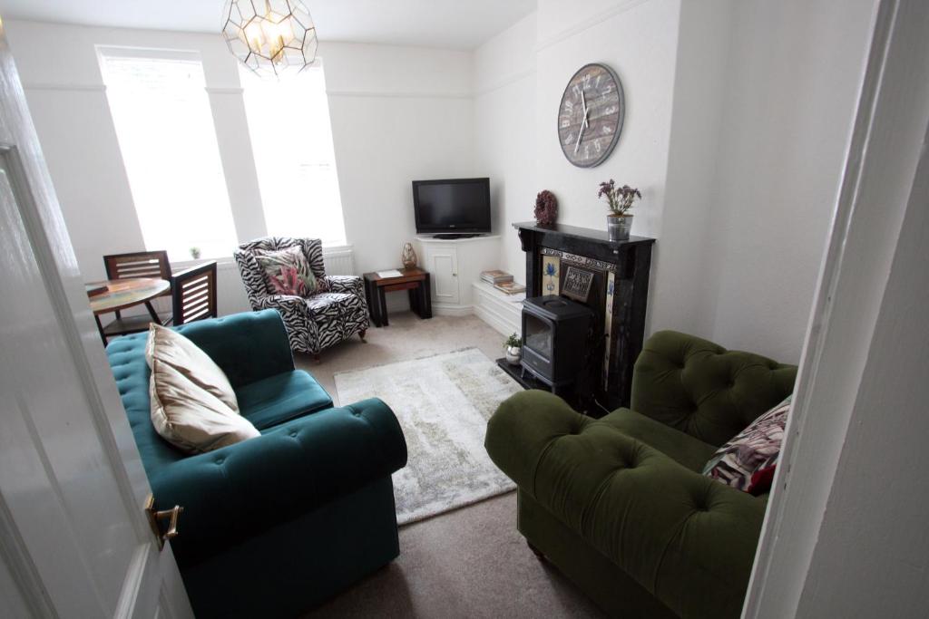 利姆Lymm Village Apartment的客厅配有两把绿色椅子和壁炉