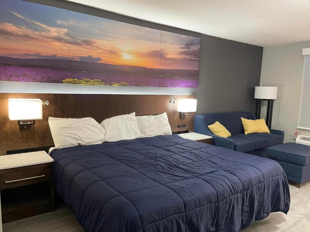 埃尔金斯Luxor Inn & Suites, a Travelodge by Wyndham的一间卧室配有一张蓝色的大床和一张沙发
