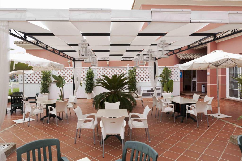 马塔拉斯卡尼亚斯Hostal Rte. Casa Miguel的庭院配有白色的桌椅和白色的遮阳伞。