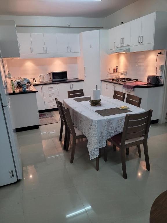 苏瓦Meadroad homestay &Tours的一间带桌椅的厨房和一间带白色橱柜的厨房