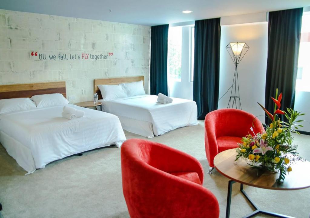 怡保Hotel Pi Ipoh的酒店客房带两张床和一张桌子以及椅子。