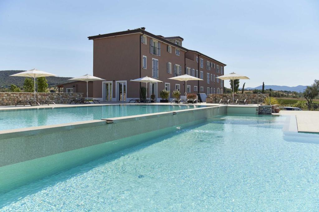 福洛尼卡Riva Toscana Golf Resort & SPA的大楼前的蓝色海水游泳池