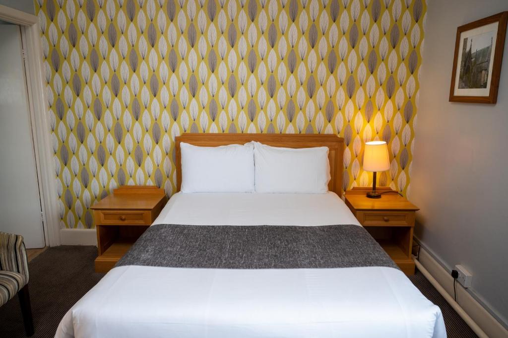 伯恩茅斯Commodore Hotel by Greene King Inns的一间卧室配有白色的床和两张床头柜。