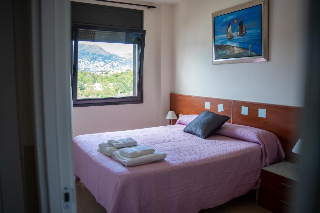 罗萨斯DUPLEX COMFORT MIL.LENI ROSES -HUTG-026971的一间卧室配有一张带紫色床单的床和窗户。