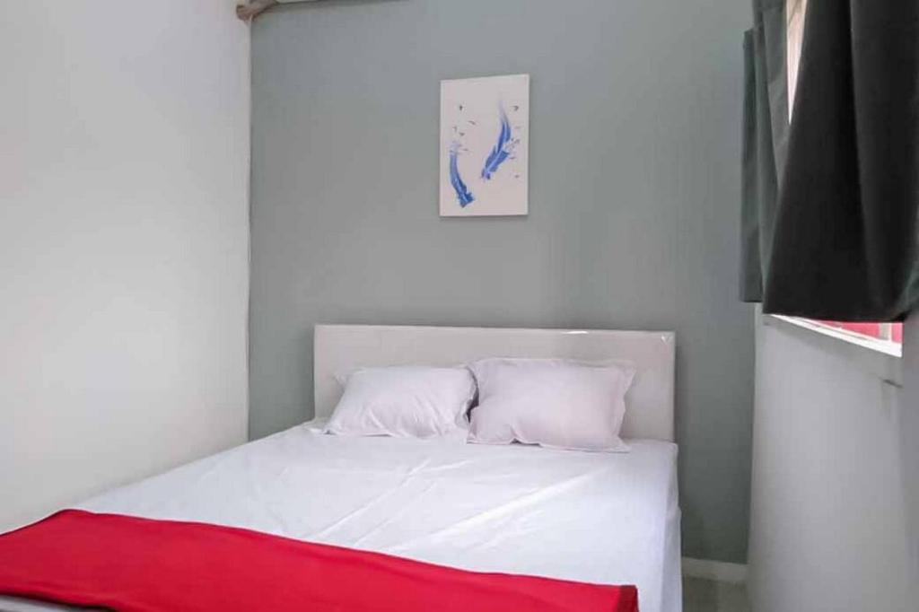 MagetanRedDoorz near Alun Alun Magetan的卧室配有白色的床和红色毯子