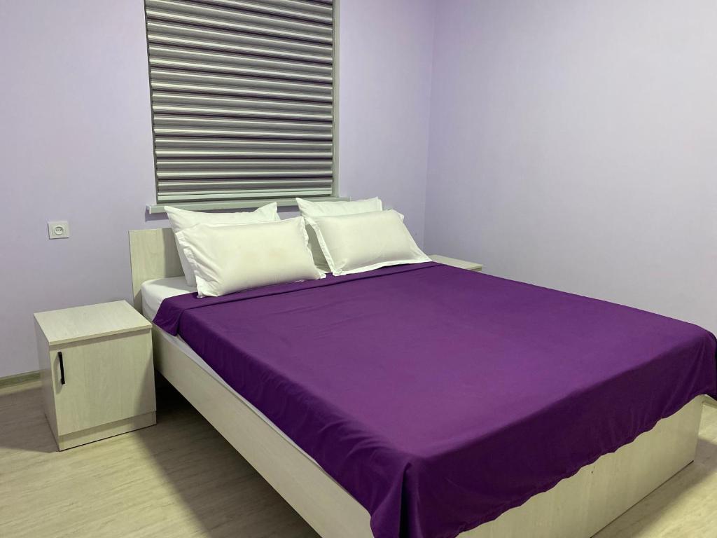 TürkistanApart House的一张带紫色床单和白色枕头的床