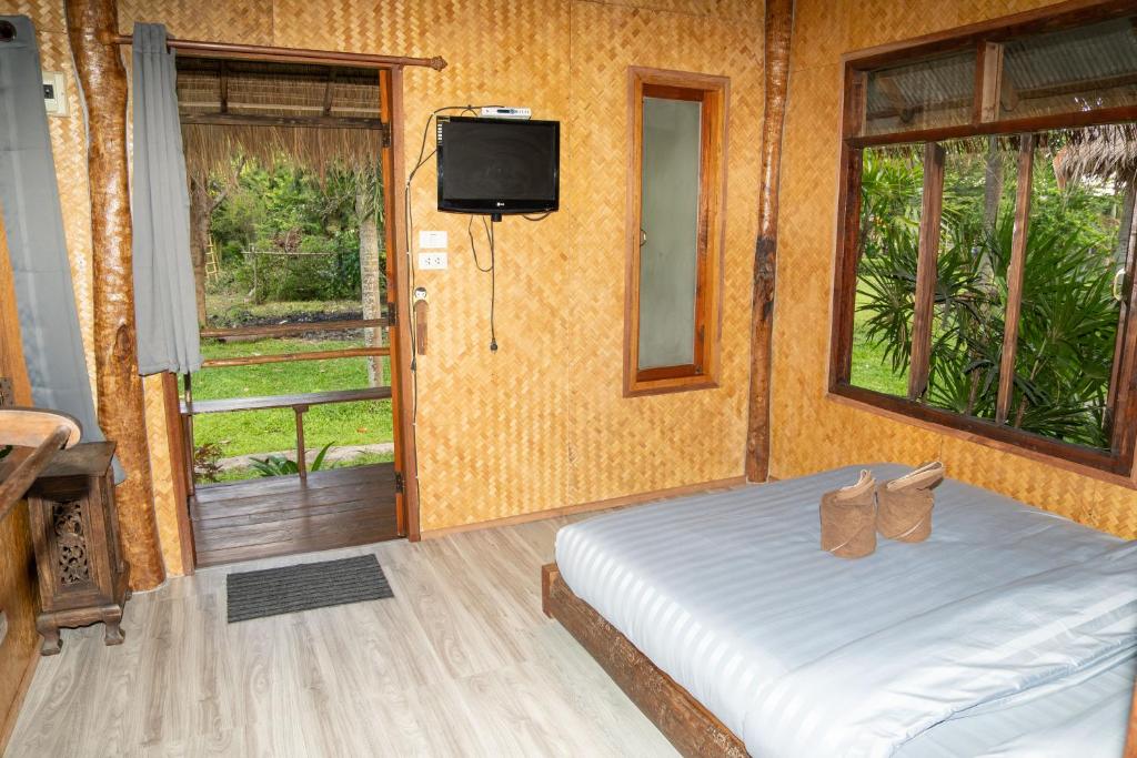拜县Butterfly Hostel, Pai的一间卧室设有一张床、电视和窗户