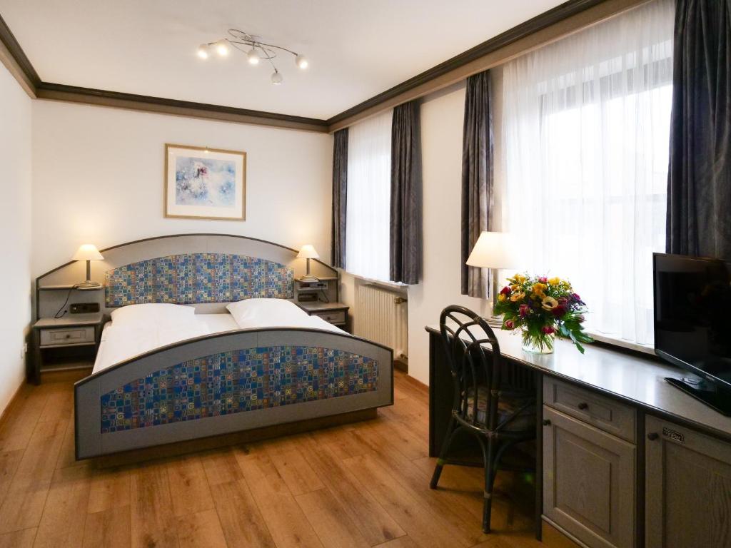 海瑞星阿莫斯Seehotel Pegasus的一间卧室配有一张床、一张书桌和一台电视