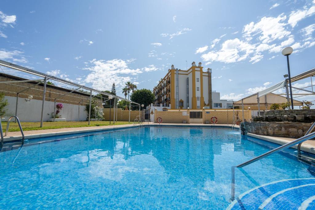 奇克拉纳－德拉弗龙特拉Hotel Balneario de Chiclana的一座蓝色的大型游泳池,其建筑背景为: