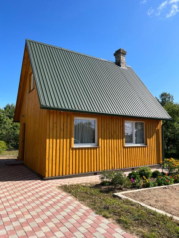 卢扎Brīvdienu namiņš的一间黄色的小房子,屋顶是 ⁇ 