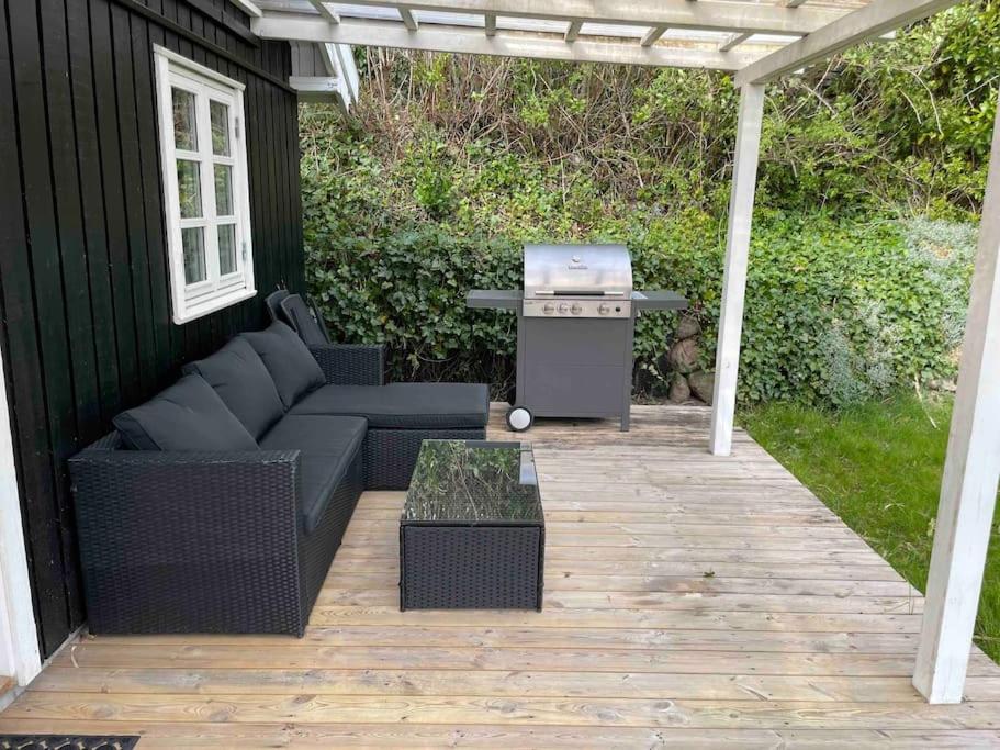 斯文堡Hyggeligt anneks på Thurø, tæt på vandet.的一个带烧烤架、沙发和桌子的庭院