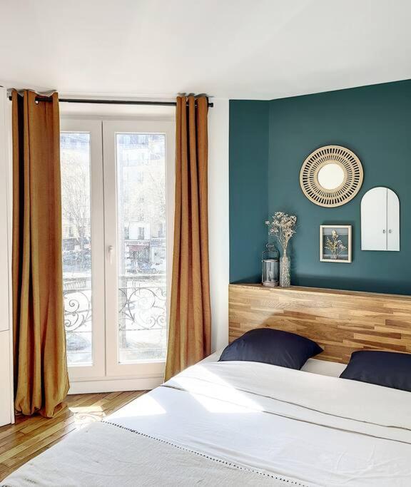 巴黎Charmant appartement parisien, spacieux & lumineux的一间卧室配有一张蓝色墙壁的床和一扇窗户