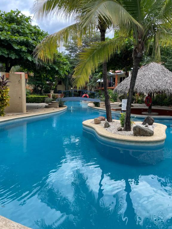 科克Cocomarindo Condo #72的度假村内棕榈树游泳池