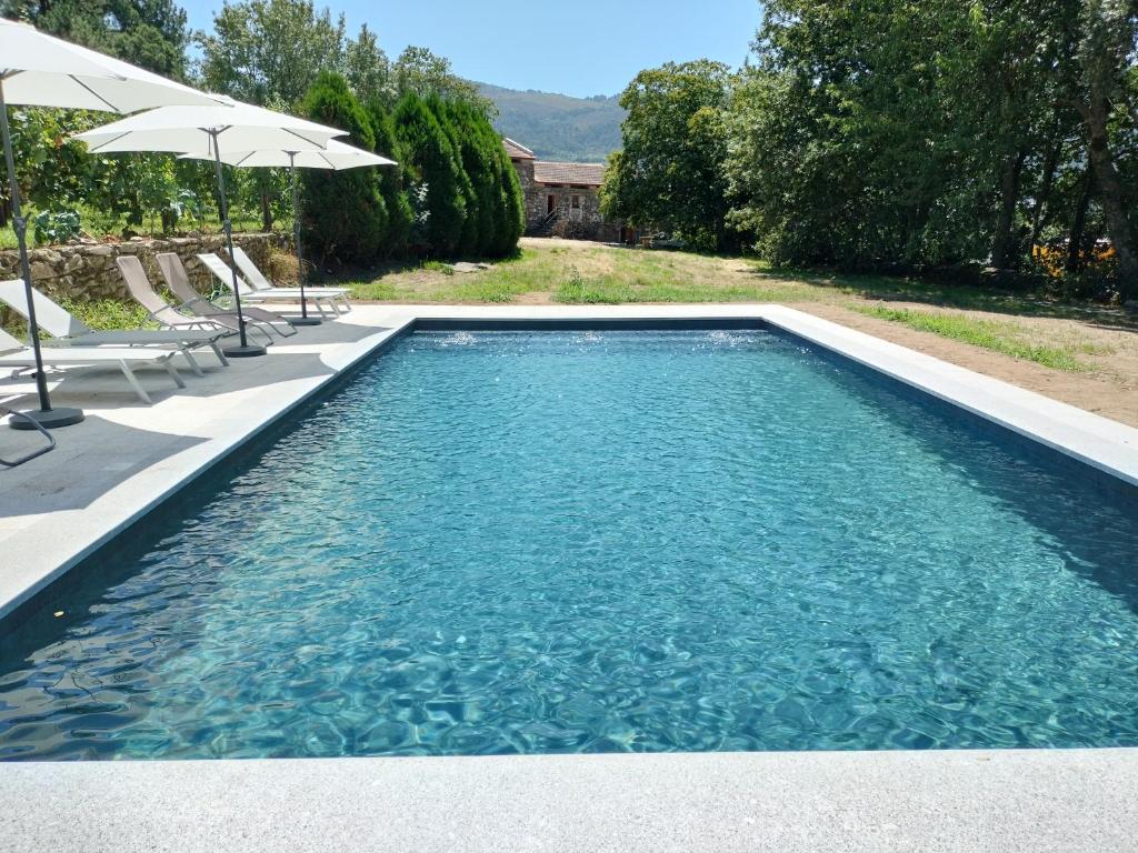 梅尔加科Casa das Bouças的一个带蓝色水和遮阳伞的游泳池
