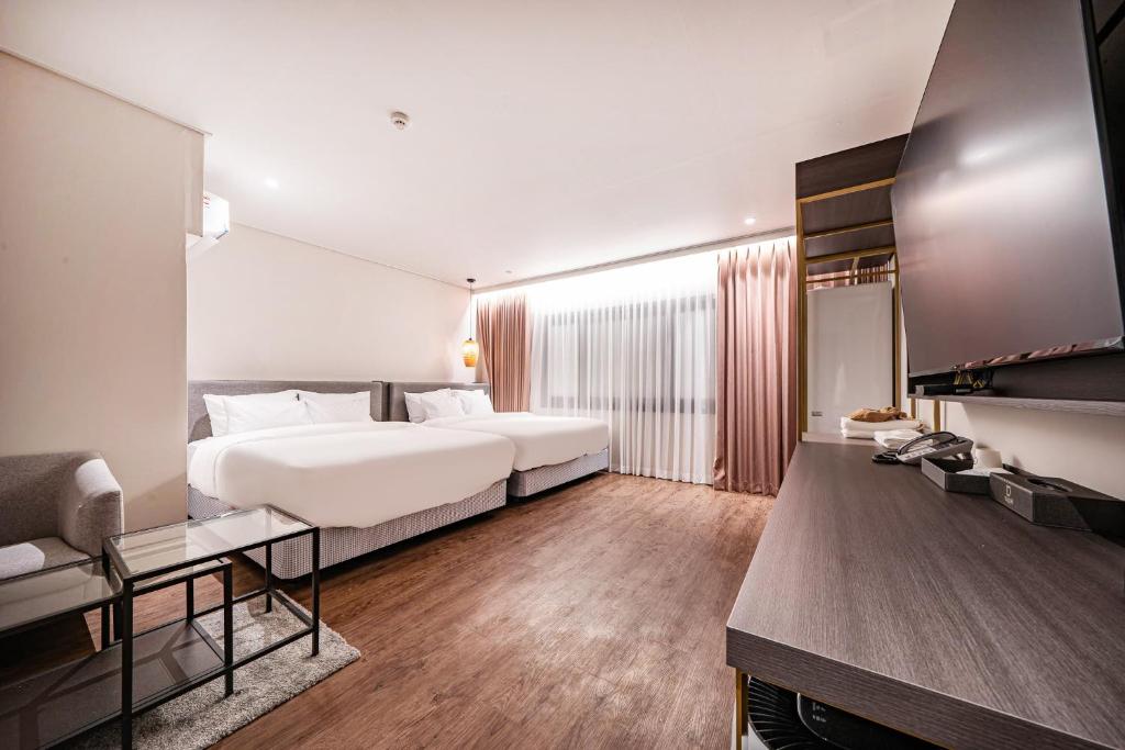 木浦市Cloud in Hotel Mokpo Peace Square的酒店客房设有一张大床和一台电视机。