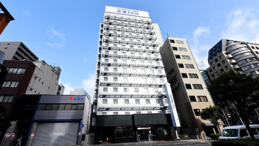 神户Toyoko Inn Kobe Sannomiya eki Shiyakusho Mae的一座高大的建筑,旁边有一个标志