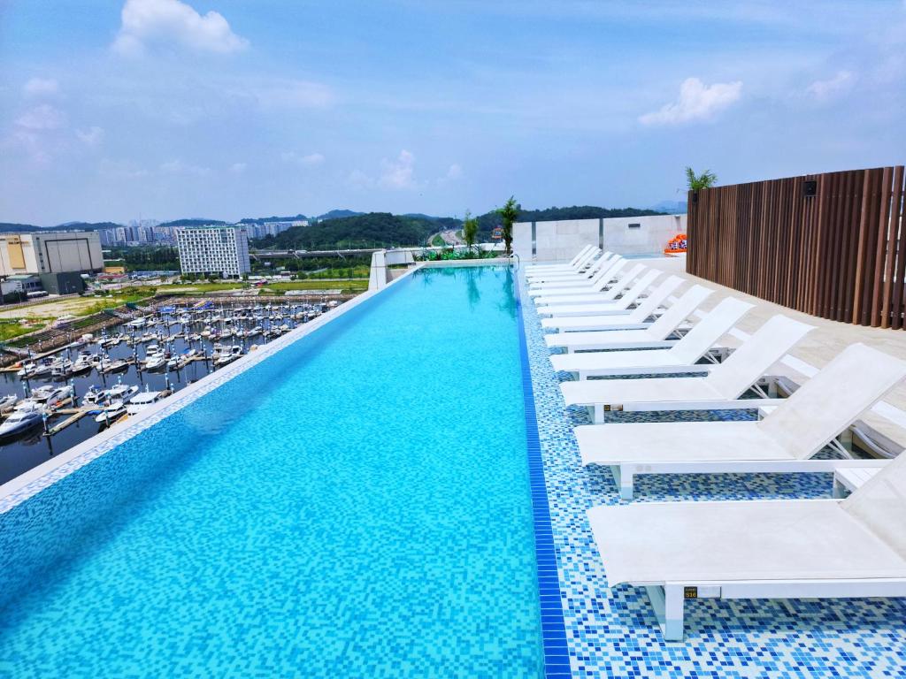 金浦Hotel Marinabay Seoul Ara的一个带白色躺椅和船只的大型游泳池