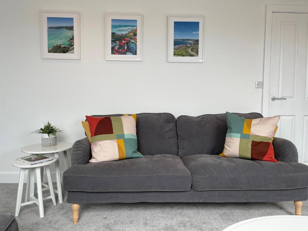 彭赞斯Stunning Town Centre Penthouse w/ Sea Views的客厅里一张灰色的沙发,墙上挂着照片