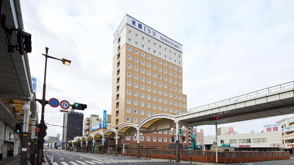 岩国市Toyoko Inn Iwakuni eki Nishi guchi的一座高大的建筑,位于一条城市街道上,有一座桥