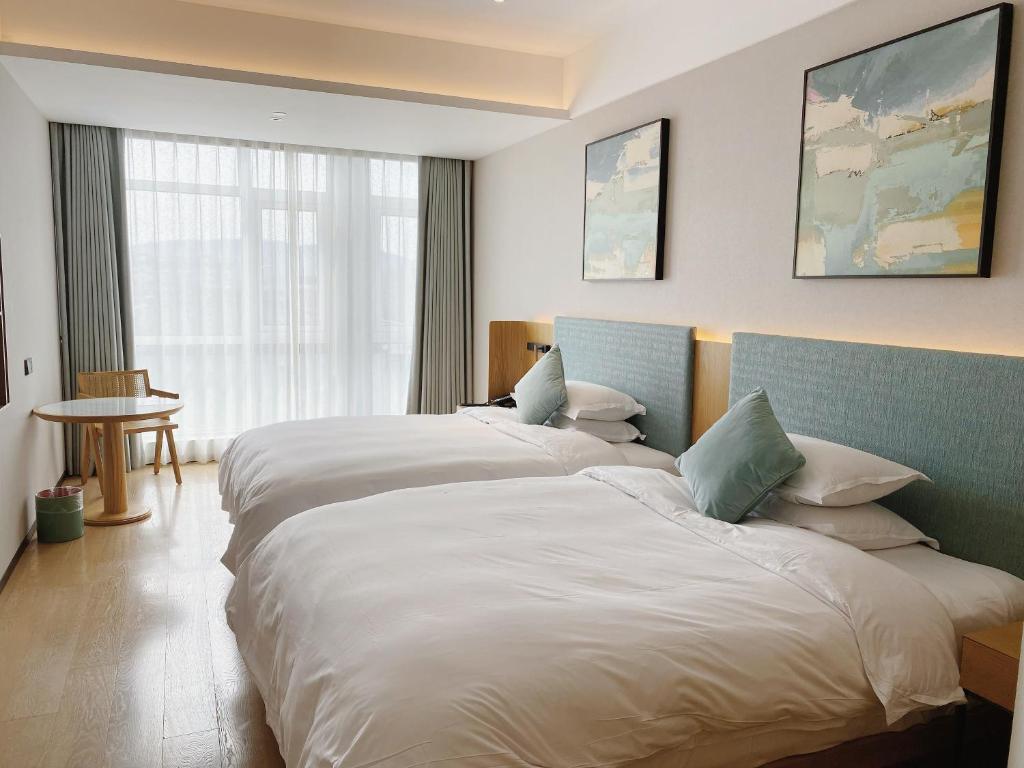 杭州之江印象君亭酒店(杭州转塘中国美院店）的酒店客房设有两张床和窗户。
