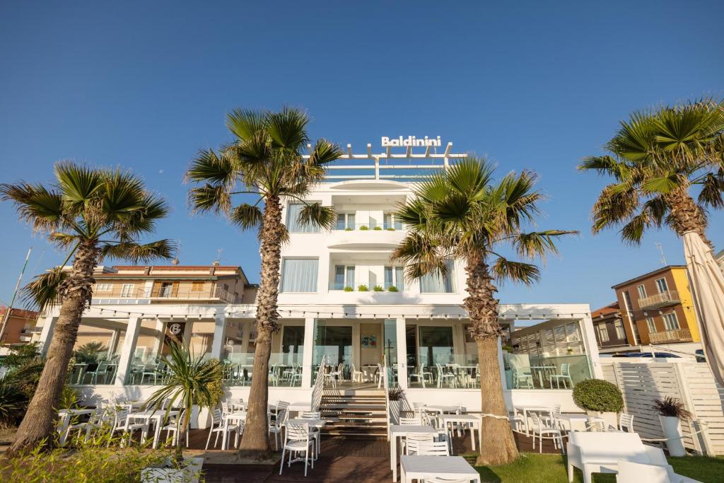 里米尼巴尔迪尼尼酒店的一座白色的建筑,前面有棕榈树