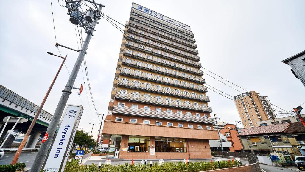 大阪Toyoko Inn Osaka Kadoma-shi Ekimae的一座高大的建筑,旁边有一个标志