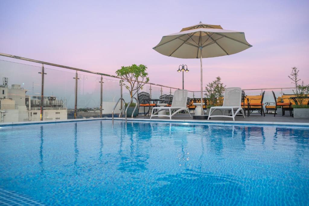 河内Anatole Hotel Hanoi的一个带椅子和遮阳伞的游泳池