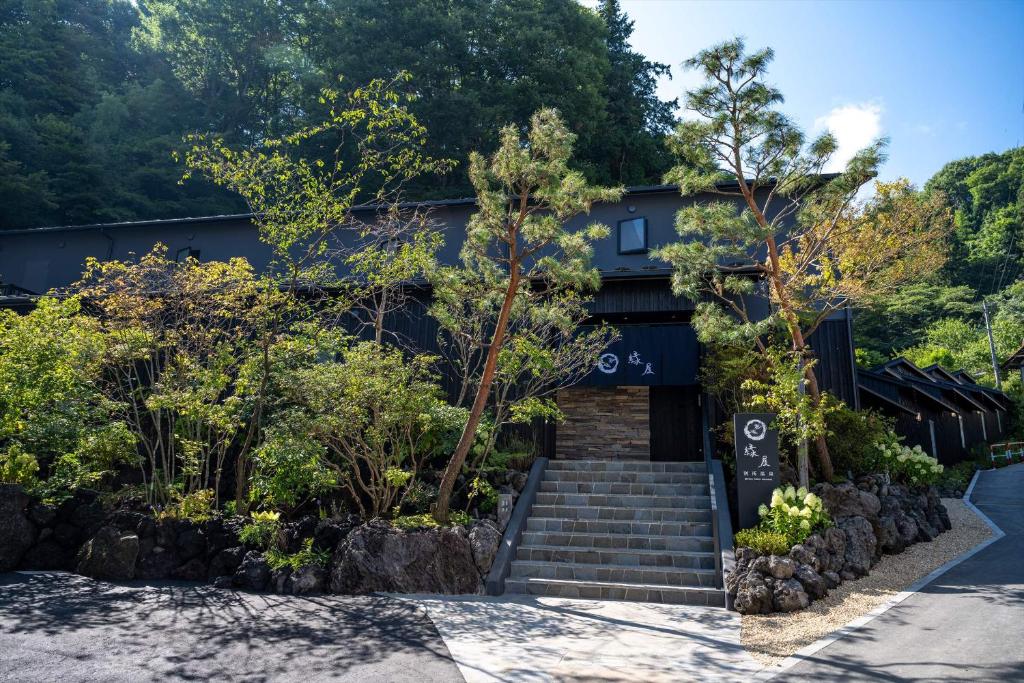 上田市Bessho Onsen Midoriya的前面有楼梯和树木的建筑