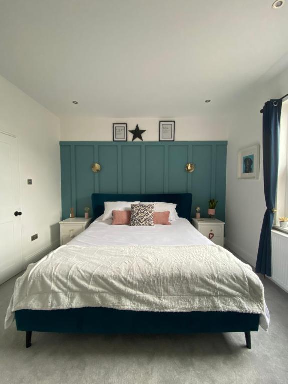 格兰瑟姆Luxury Spacious Renovated Townhouse的一间卧室配有一张大床和蓝色床头板