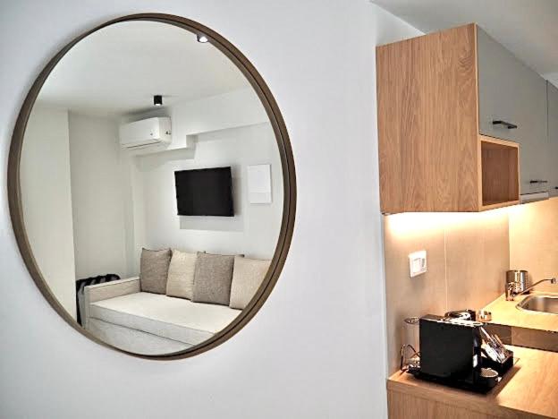 伊里斯斯La Mer Luxury Apartments的镜子反射着一个配有沙发的房间和一个厨房
