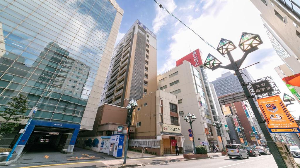埼玉市Toyoko Inn Omiya-eki Higashi-guchi的一条城市街道,有高大的建筑和街灯
