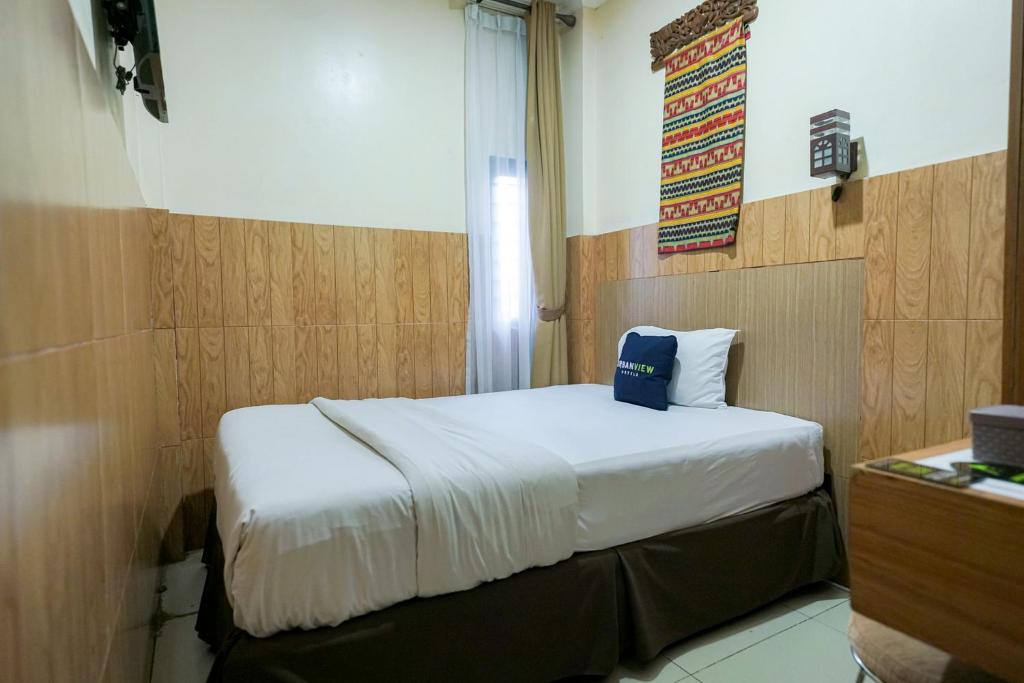 PondoklangUrbanview Hotel 58 Bintaro by RedDoorz的卧室配有一张挂有墙上标志的床