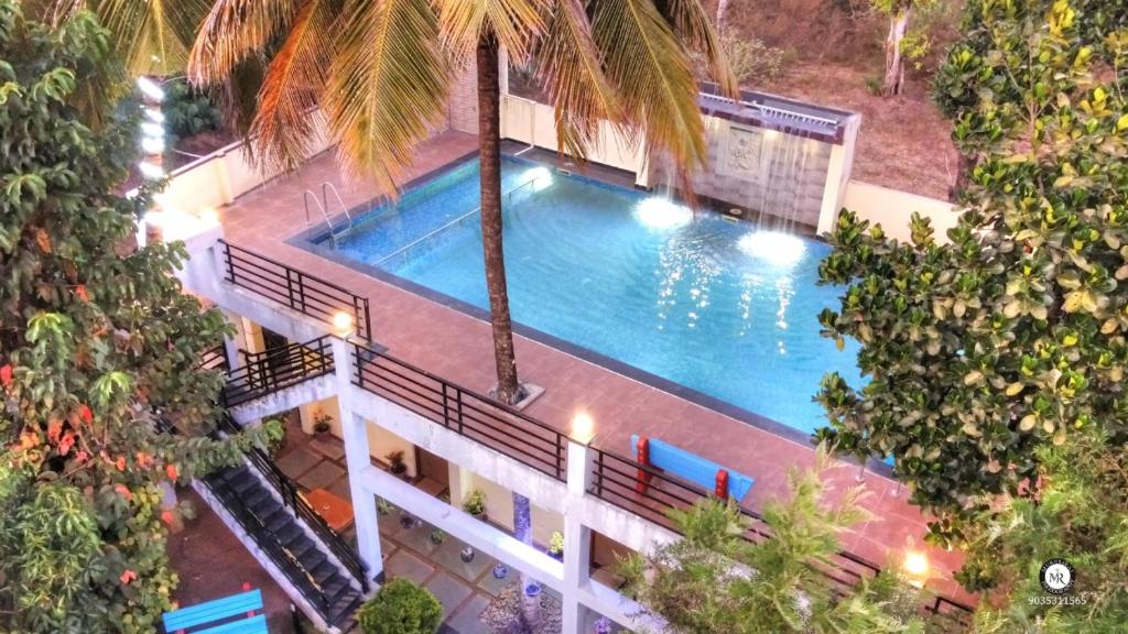马迪凯里Coorg Avani Holiday Inn的享有棕榈树游泳池的顶部景致