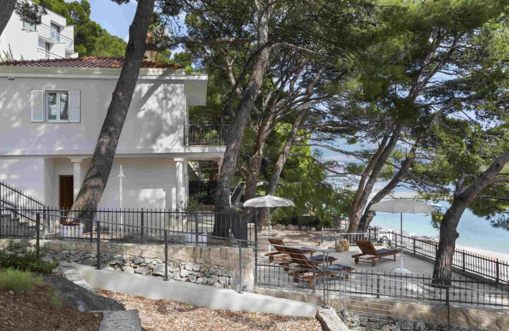 布雷拉Villa Berulia的海滩上带椅子和遮阳伞的白色房子