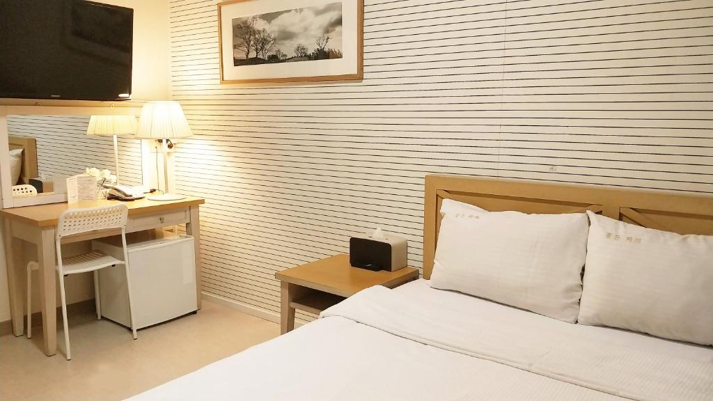 济州市金园酒店的一间卧室配有一张床和一张带电脑的书桌