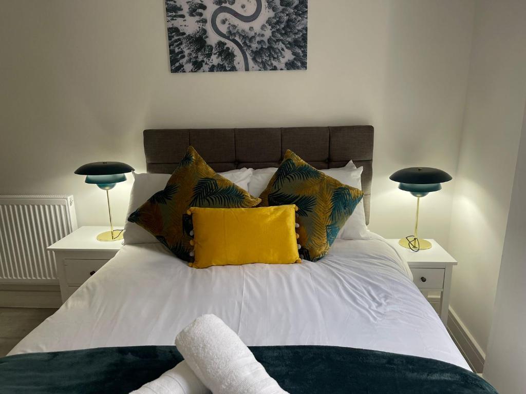 伍尔弗汉普顿Kingdom apartments的一间卧室配有一张带黄色枕头的床和两盏灯。