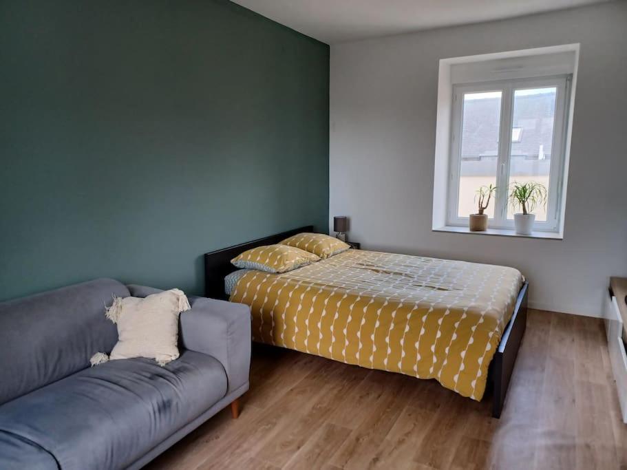 圣布里厄Maison de ville - terrasse sud, a 10 min des plages的一间卧室配有一张床、一张沙发和一个窗口