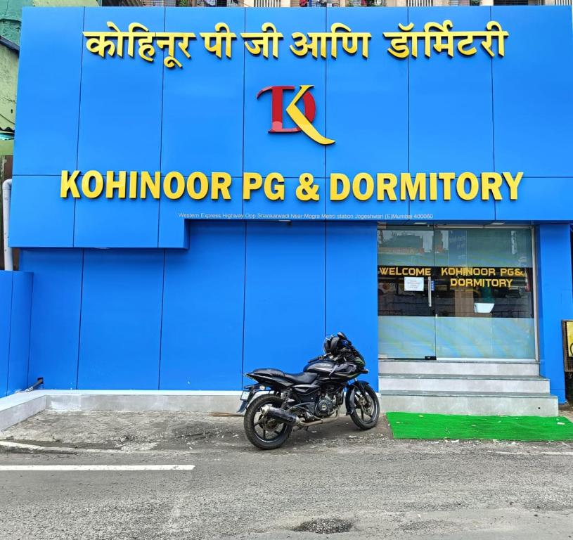 孟买Kohinoor Dormitory的停在蓝色建筑前面的摩托车