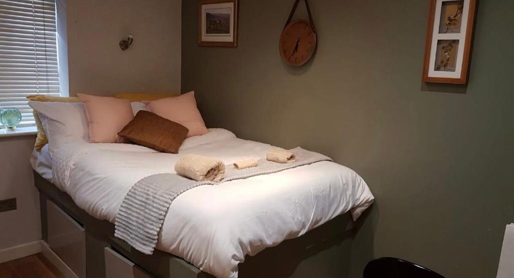 德比Affordable Flats - Derby City Centre的一张带两条毛巾的床和墙上的时钟