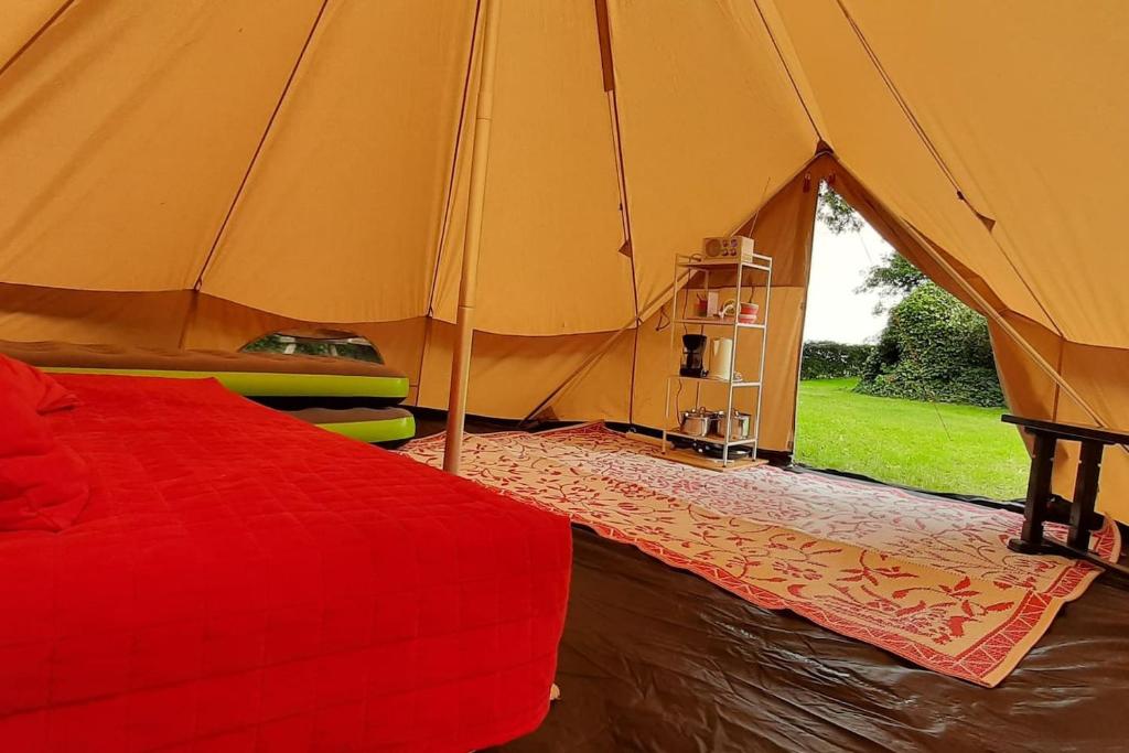 SchagerbrugSfeervolle Tipi tent dicht bij de kust.的一间帐篷内带红色床的卧室