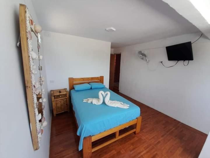 通贝斯La palmera zorritos的一间卧室配有一张带蓝色床单的床和一台电视。