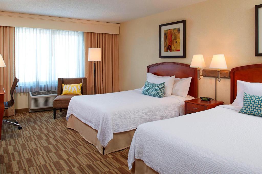 森特尼尔丹佛南园梅多斯购物中心万怡酒店的酒店客房,配有两张床和椅子
