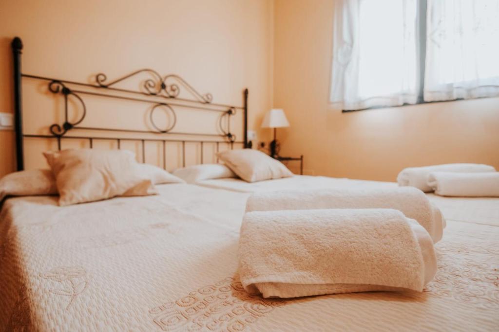特鲁希略Conde de la Encina 16的一间卧室设有两张带白色床单的床和窗户。
